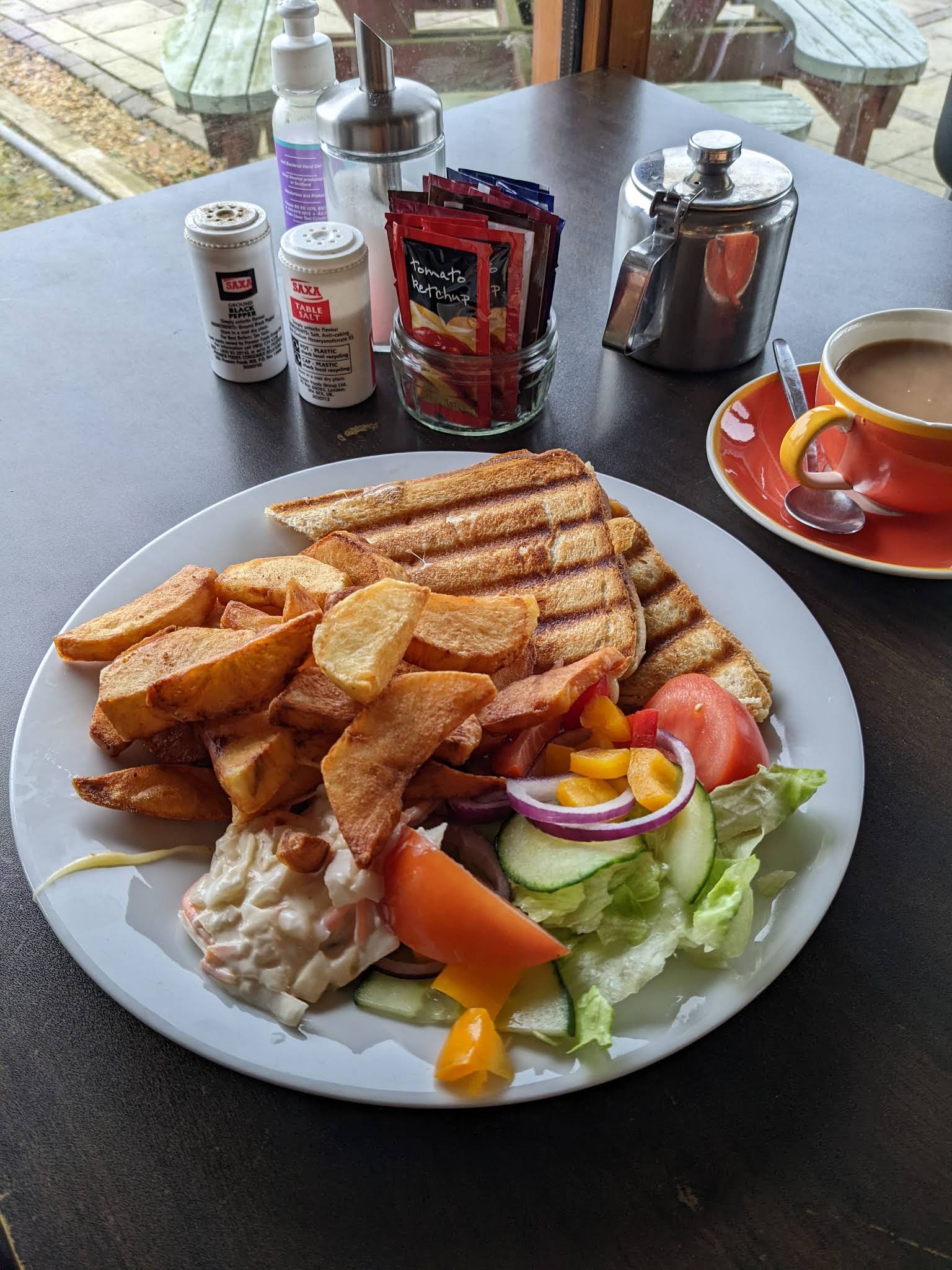 A toastie, homemade-style chips and salad on a complete white plate at The 4 Seasons Eatery